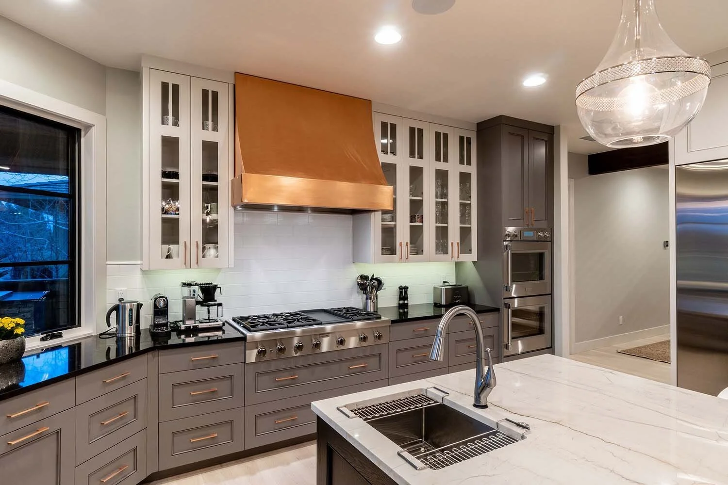 Discover this stunning modern kitchen, a highlight in a luxury custom home by Pacwest Builders. Featuring sophisticated gray cabinets, a crisp white subway tile backsplash, and premium stainless steel appliances, it blends both style and function. Bl