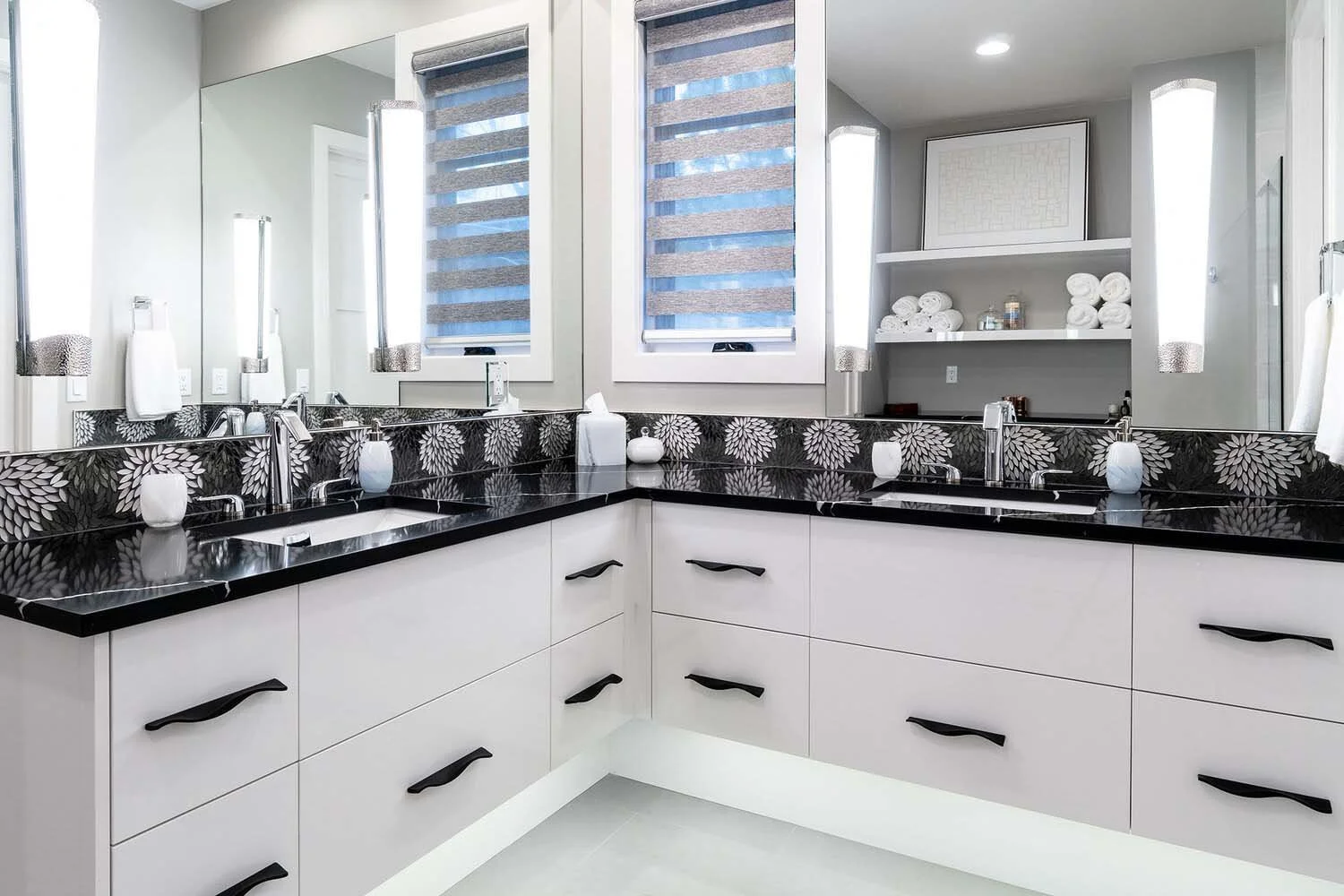 This elegant modern bathroom vanity, a testament to Pacwest Builders' attention to detail in luxury custom homes, features a distinctive black floral-patterned countertop with two sleek sinks. A large mirror beautifully complements the clean white ca