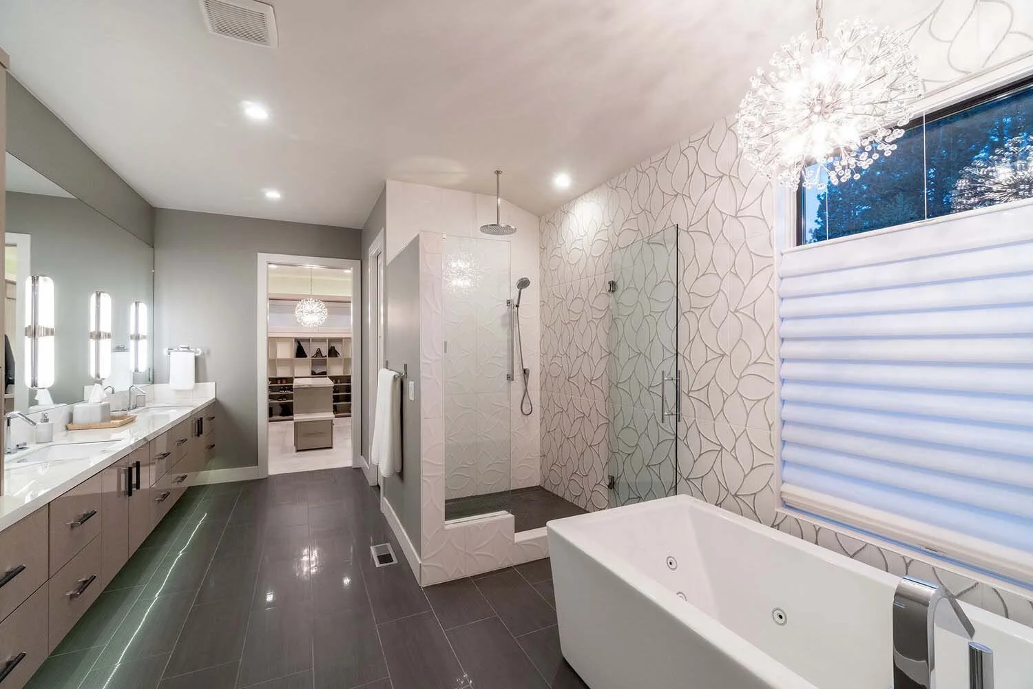 This spacious and sophisticated bathroom, a key feature in a luxury custom home by Pacwest Builders, showcases unique light fixtures and targeted illumination for a perfect getting-ready space. The expansive, spa-like shower space adds a touch of ele