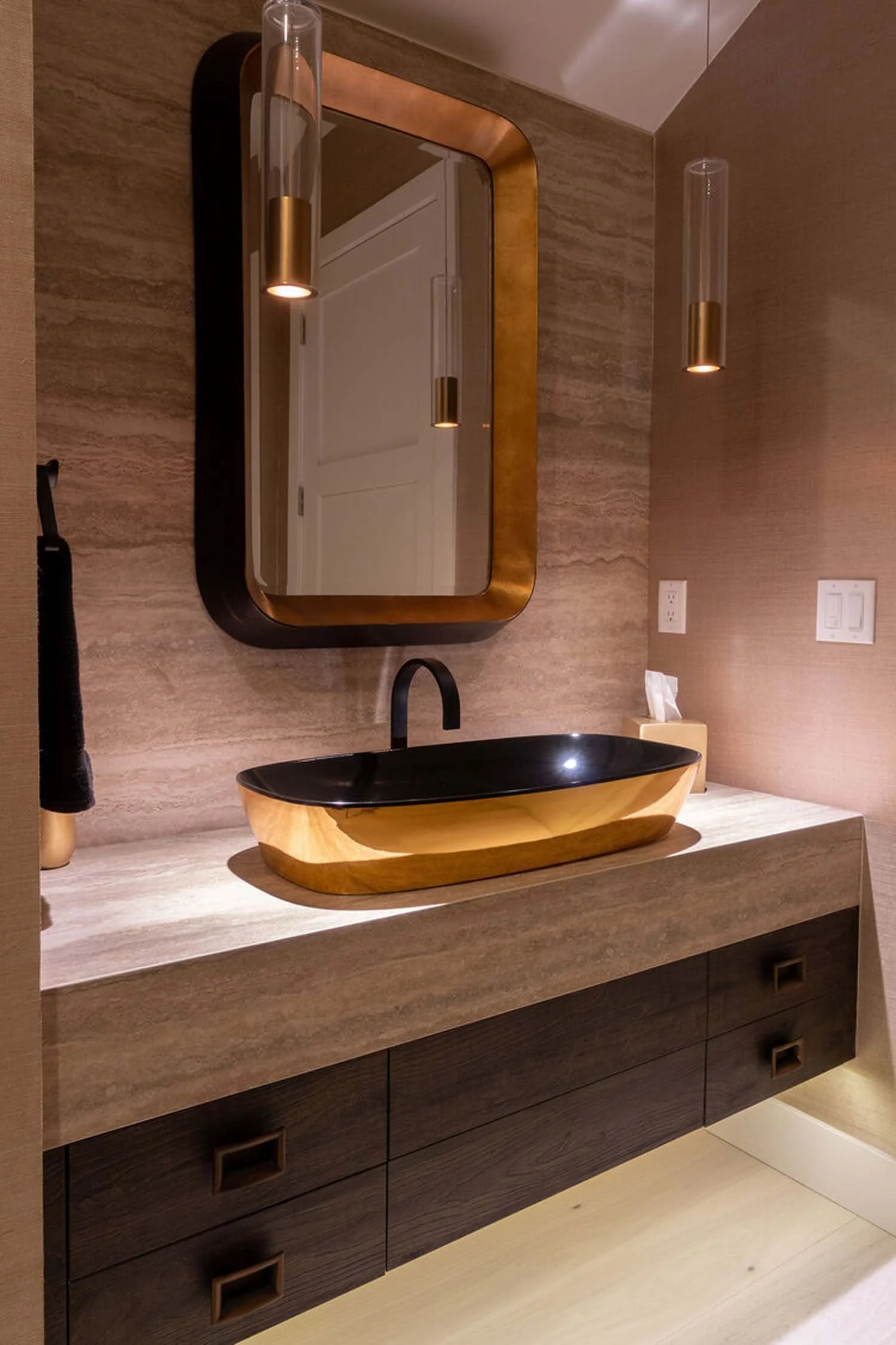 "This striking modern bathroom vanity, a highlight in a luxury custom home by Pacwest Builders, features a unique black and wood vessel sink that stands as a design statement. Above, a sleek rectangular mirror with a sophisticated gold frame is perfe