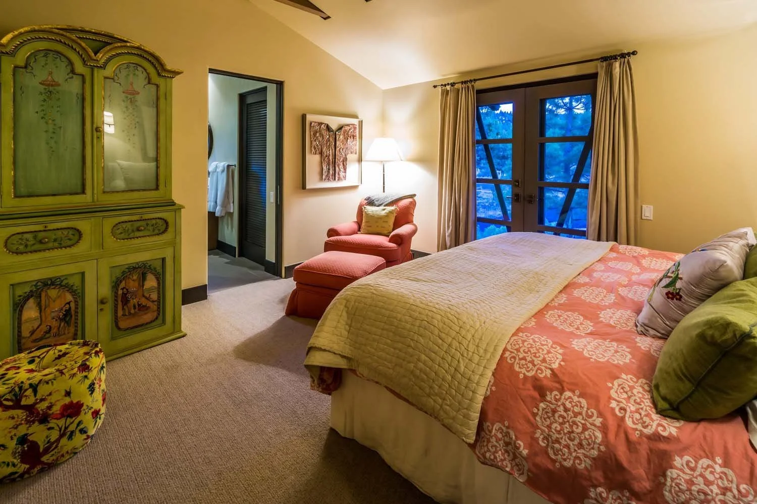 This whimsical and cozy bedroom, a unique space within a luxury custom home built by Pacwest Builders with Hayes Inc. design in North Rim, offers a vibrant escape. A striking green painted armoire with detailed artwork adds a touch of bohemian flair.