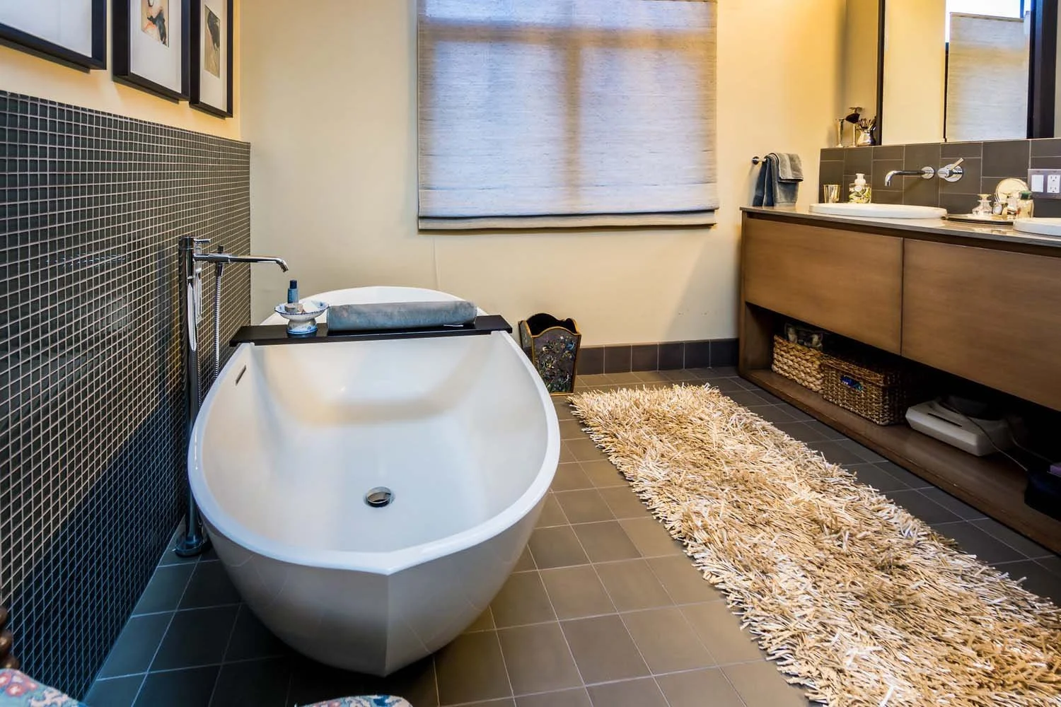 This serene modern bathroom, a highlight in a luxury custom home built by Pacwest Builders with Hayes Inc. design in North Rim, offers a spa-like retreat. It features an elegant white freestanding bathtub, perfectly complemented by a soft beige shagg