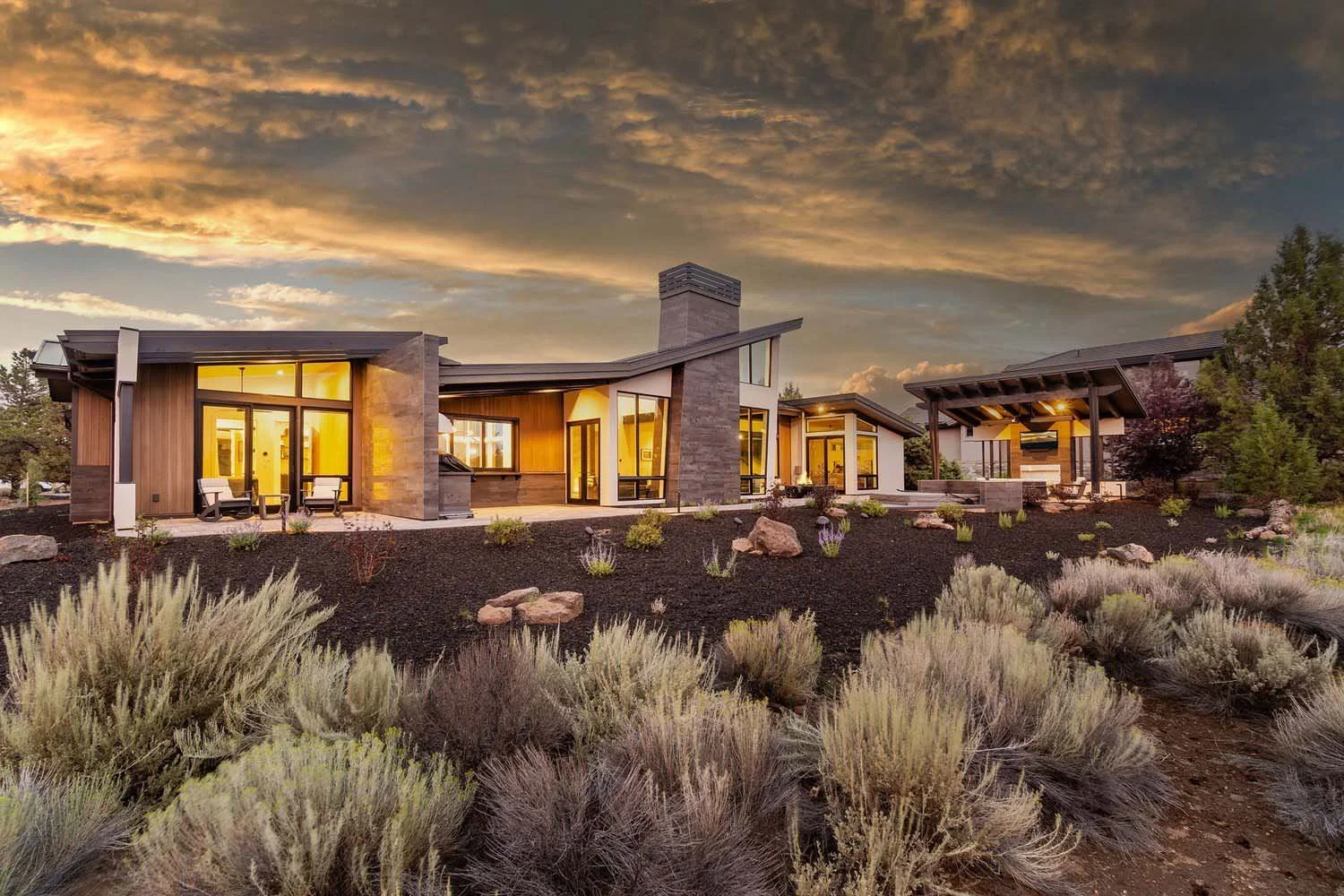 This view of the Pronghorn - Canyon View home, designed by Blair Davis, highlights its spectacular connection to the landscape. The home's design features expansive large floor-to-ceiling windows that seamlessly blend the interior with the outdoors.