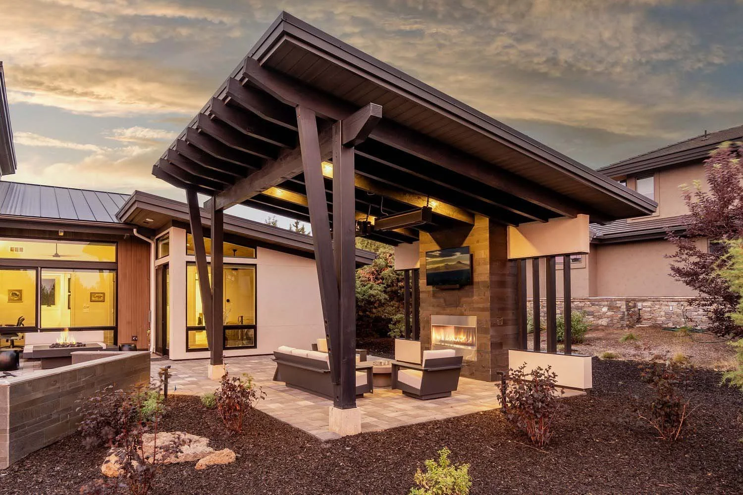 This spectacular modern outdoor patio at the Pronghorn - Canyon View home is the ultimate retreat. The space, with its distinctive angled roof, offers a covered sitting area with comfortable seating and a cozy fireplace, making it perfect for year-ro