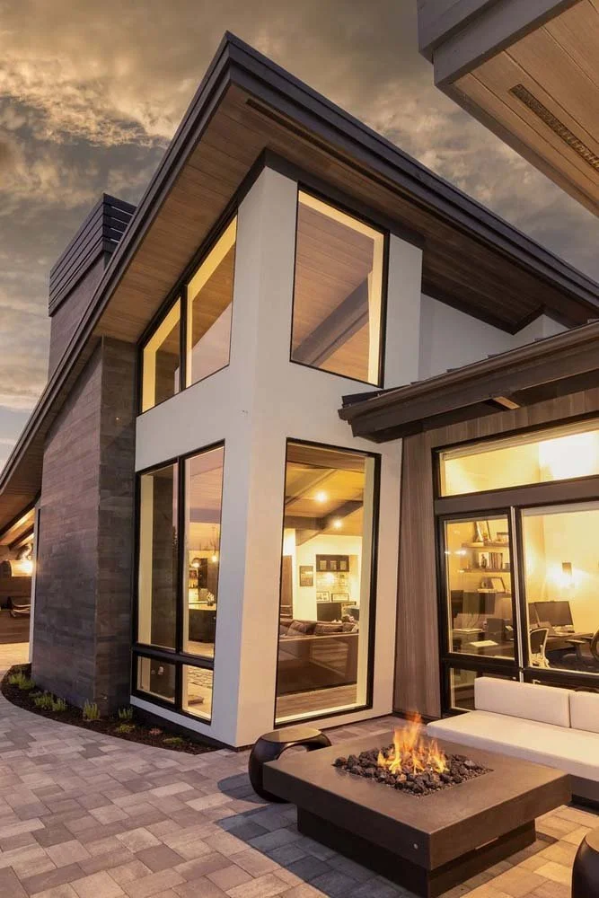 This dramatic, low-angle view of the Pronghorn - Canyon View home showcases its unique architectural design by Blair Davis. The underside of the angled roof and the striking long corner windows create a sense of dynamic flow. The home's exterior feat