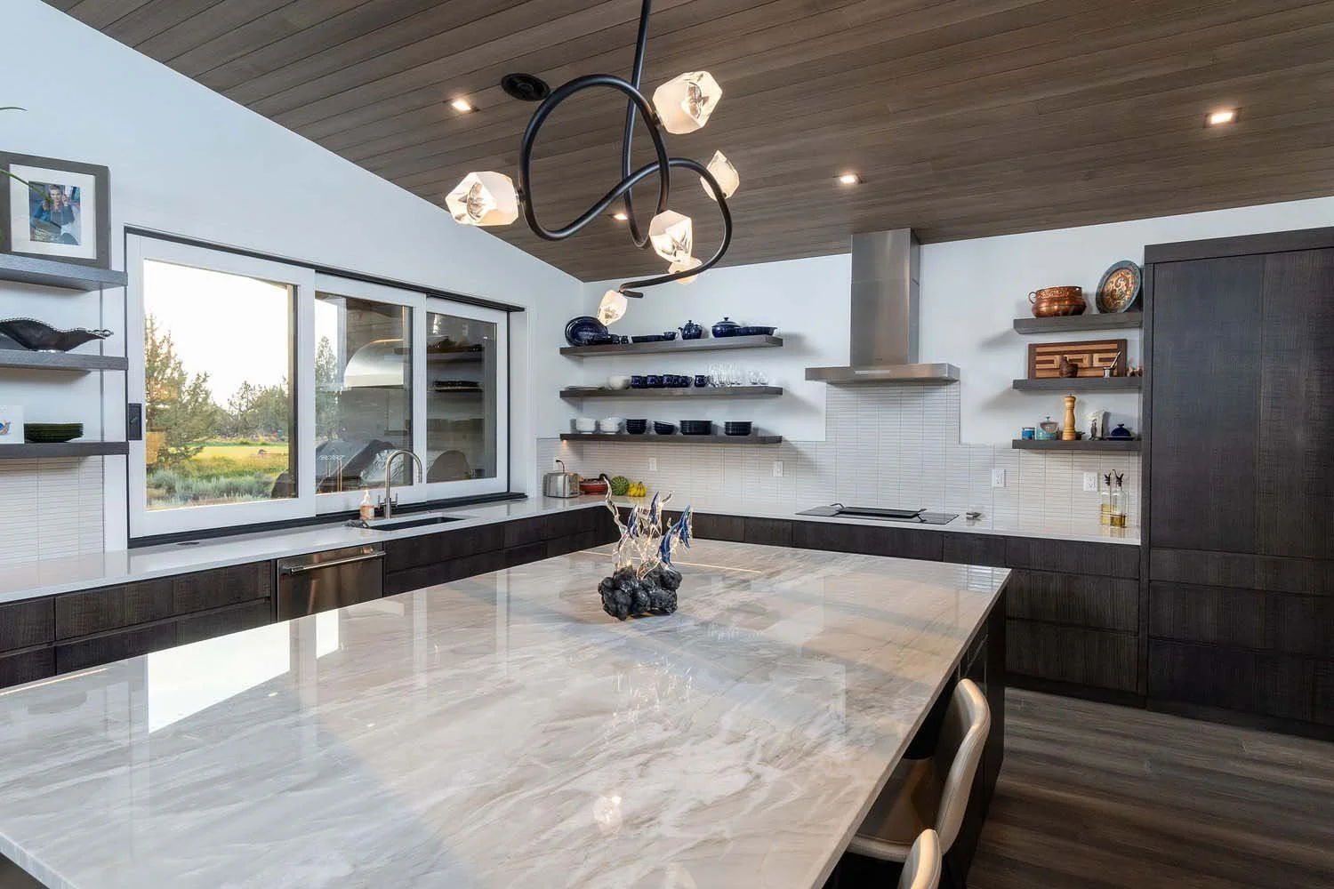 This breathtaking modern kitchen at Pronghorn - Canyon View, designed by Blair Davis, is a perfect blend of style and functionality. The centerpiece is a magnificent marble island, complemented by sleek dark wood cabinetry and a modern stainless stee
