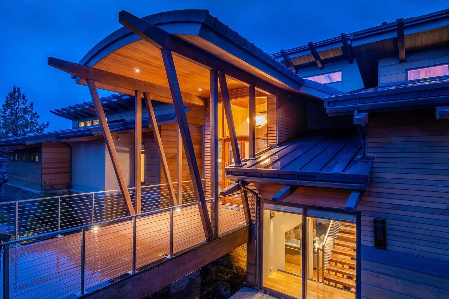 This dramatic night view showcases the covered walkway leading to the entrance of this beautiful North Rim - Wild Rye home. The design features a modern handrail and elegant open beams that lead to the home. The modern wooden house is beautifully ill