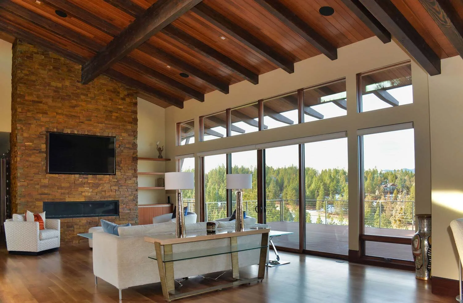 As experienced builders of luxury custom homes in Central Oregon, Pacwest Builders crafted this beautiful living room at North Rim - Wild Rye. The space, with interiors by Kristy Yozamp, features a grand high wooden ceiling and a beautiful brick fire