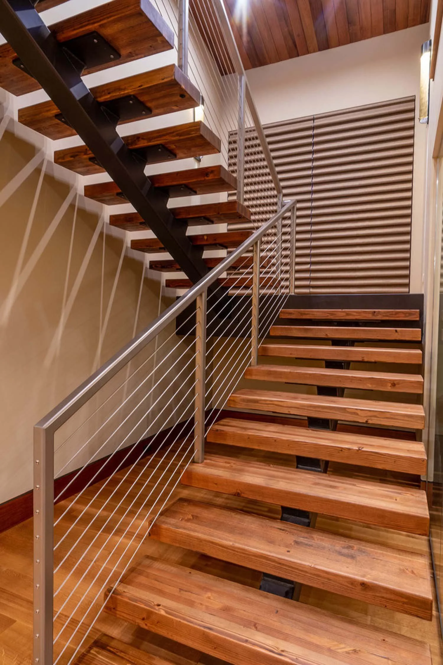 The stunning indoor staircase in the North Rim - Wild Rye home is a work of art, designed to connect spaces with elegance. This "floating-tread" staircase features beautiful floating wooden steps, supported by a sleek metal structure with a cable rai