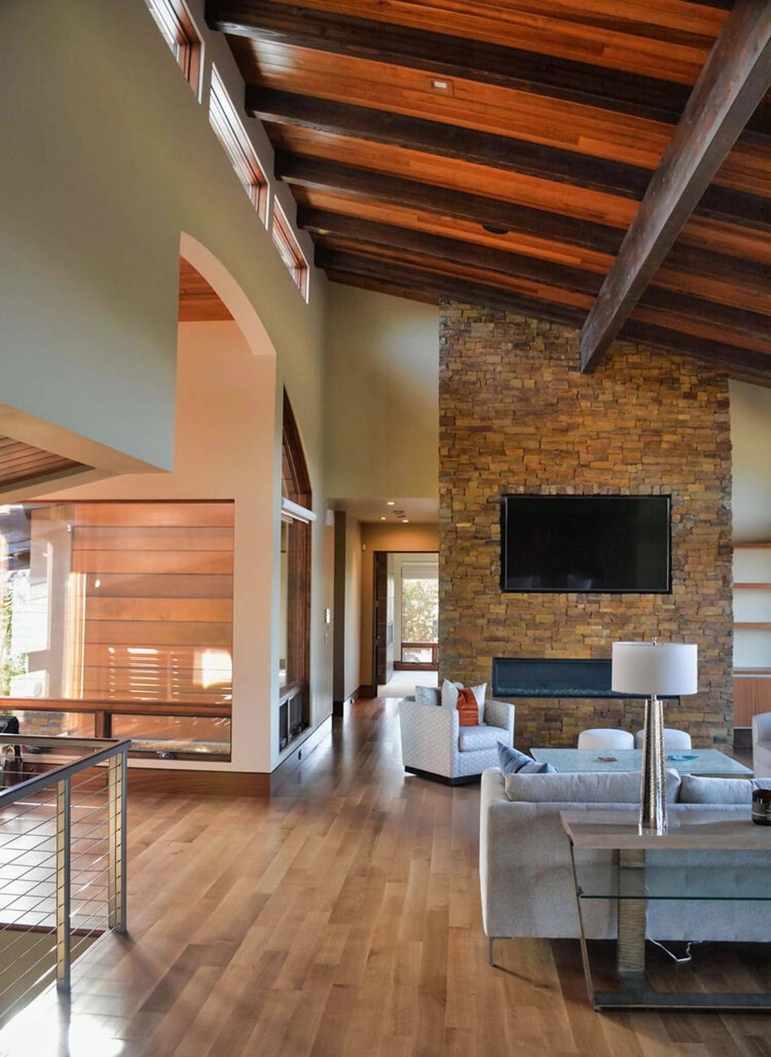 This stunning living room in the North Rim - Wild Rye home by Pacwest Builders is designed for both comfort and a connection to nature. The space features a dramatic high wooden ceiling and expansive large windows that fill the room with natural ligh