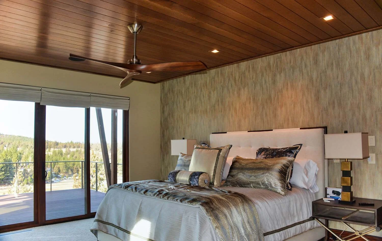 This peaceful bedroom at the North Rim - Wild Rye home by Pacwest Builders is a true retreat designed to connect seamlessly with the outdoors. The space features a large bed with multiple pillows and a stylish wooden nightstand with a lamp. The highl