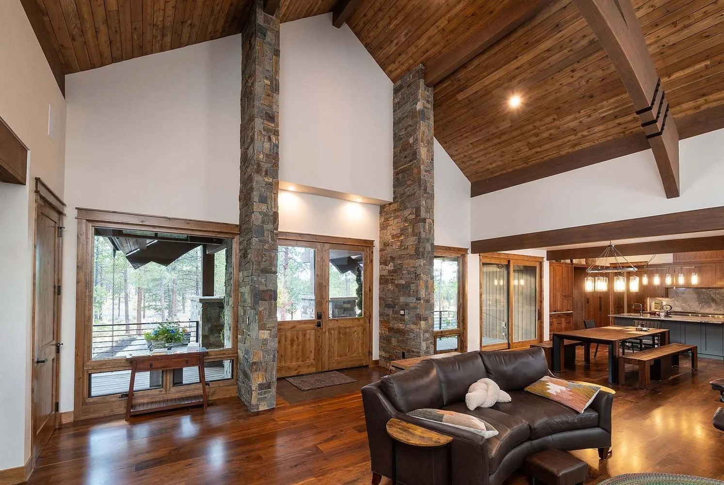 This stunning open-floor living and kitchen area at the Skyline Ranch - Imbler home by Pacwest Builders is designed for a seamless flow between spaces. A large double-door entry, framed by elegant stone pillars, opens to the living room, which leads