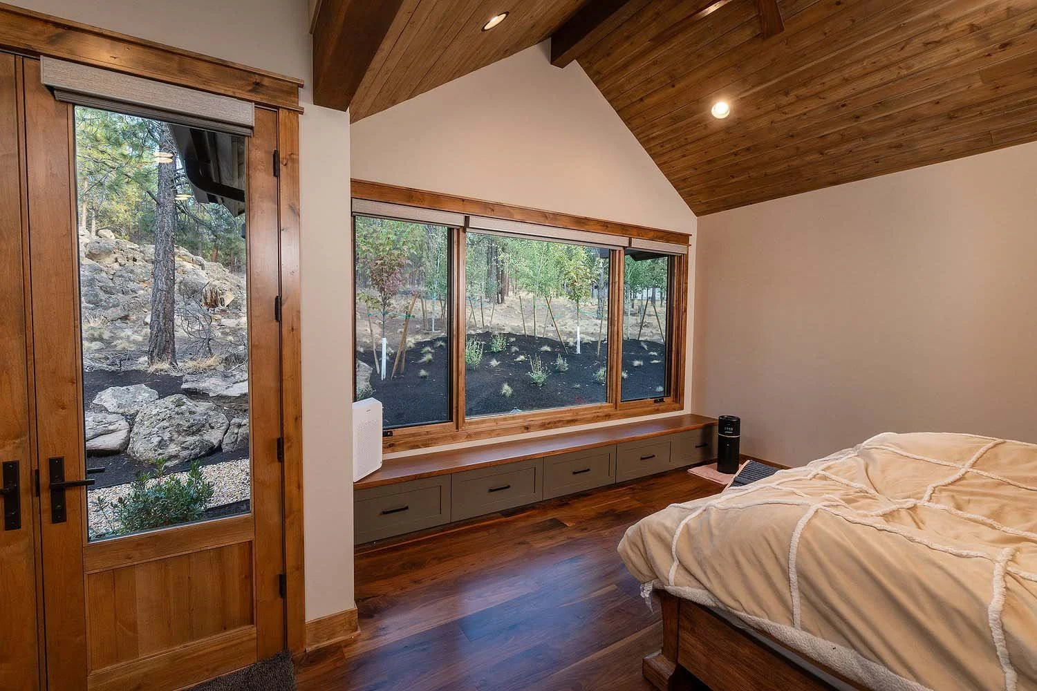 This peaceful bedroom at the Skyline Ranch - Imbler home by Pacwest Builders is a true retreat designed to connect seamlessly with the outdoors. The space features a cozy atmosphere with a beautiful wooden ceiling and warm hardwood floor. The highlig