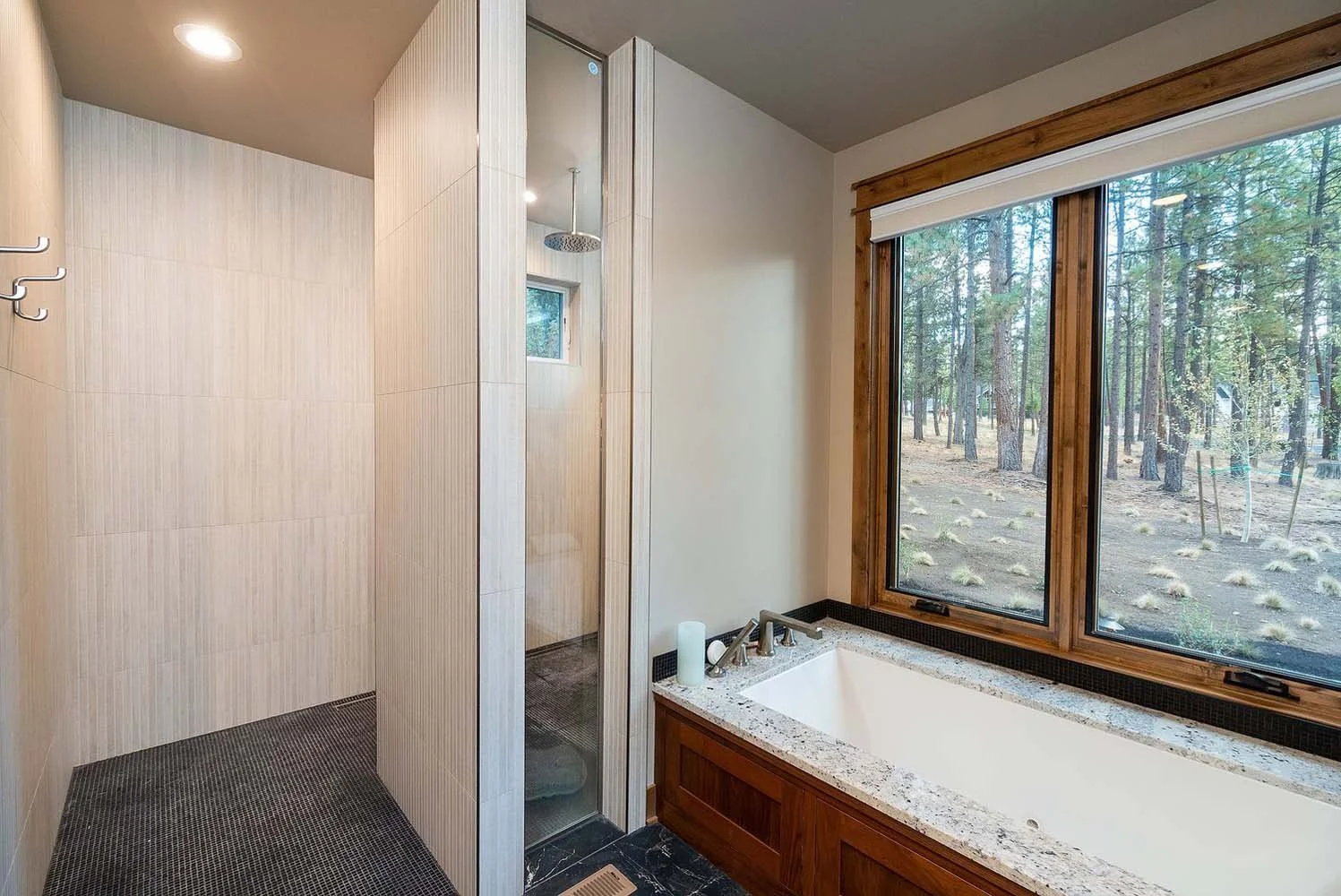 This stunning bathroom at the Skyline Ranch - Imbler home by Pacwest Builders is a perfect blend of style and a tranquil connection to nature. The luxurious large bathtub is perfectly positioned below a window, offering a beautiful forest view while