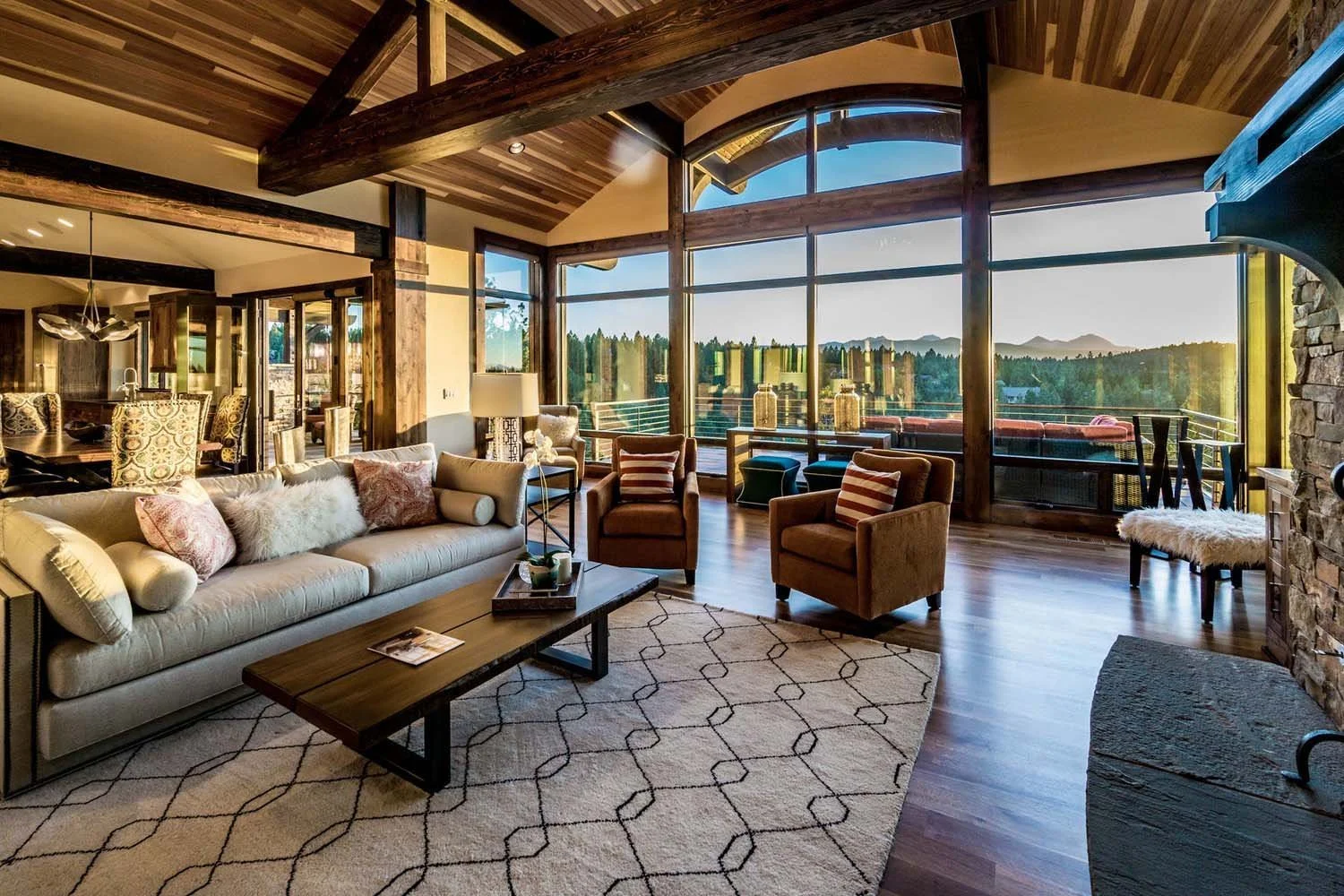 This breathtaking living room in the award-winning North Rim - Wild Rye home by Pacwest Builders is designed for both comfort and a connection to nature. Expansive large floor-to-ceiling windows perfectly frame a stunning view of trees and mountains.