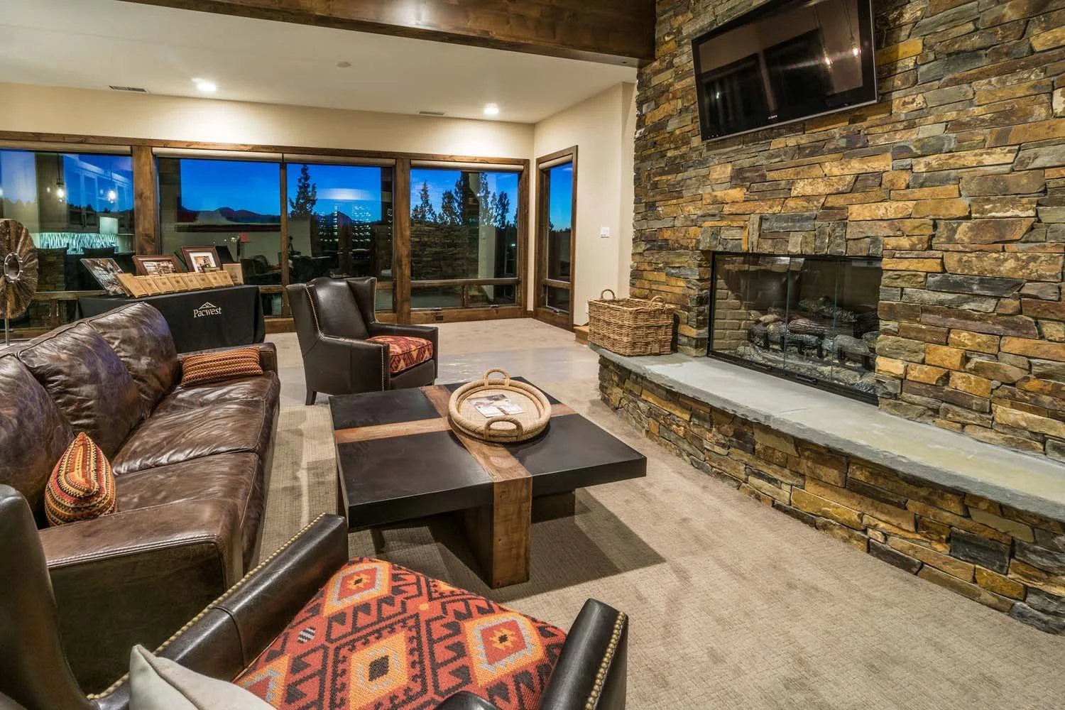 This cozy living room in the award-winning North Rim - Wild Rye home is the perfect space to unwind and connect with nature. Designed by Pacwest Builders, the room features a comfortable blend of leather and fabric furniture and a stunning stone fire
