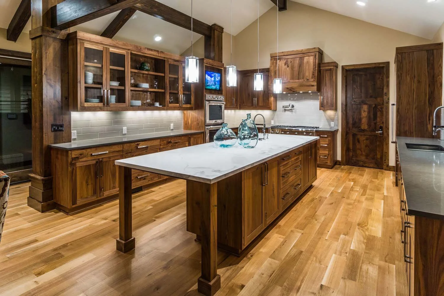 This stunning kitchen in the award-winning North Rim - Wild Rye home is a testament to sophisticated design and functionality. The space features elegant wooden cabinets, a magnificent large white marble island, and beautiful hardwood flooring. Sleek