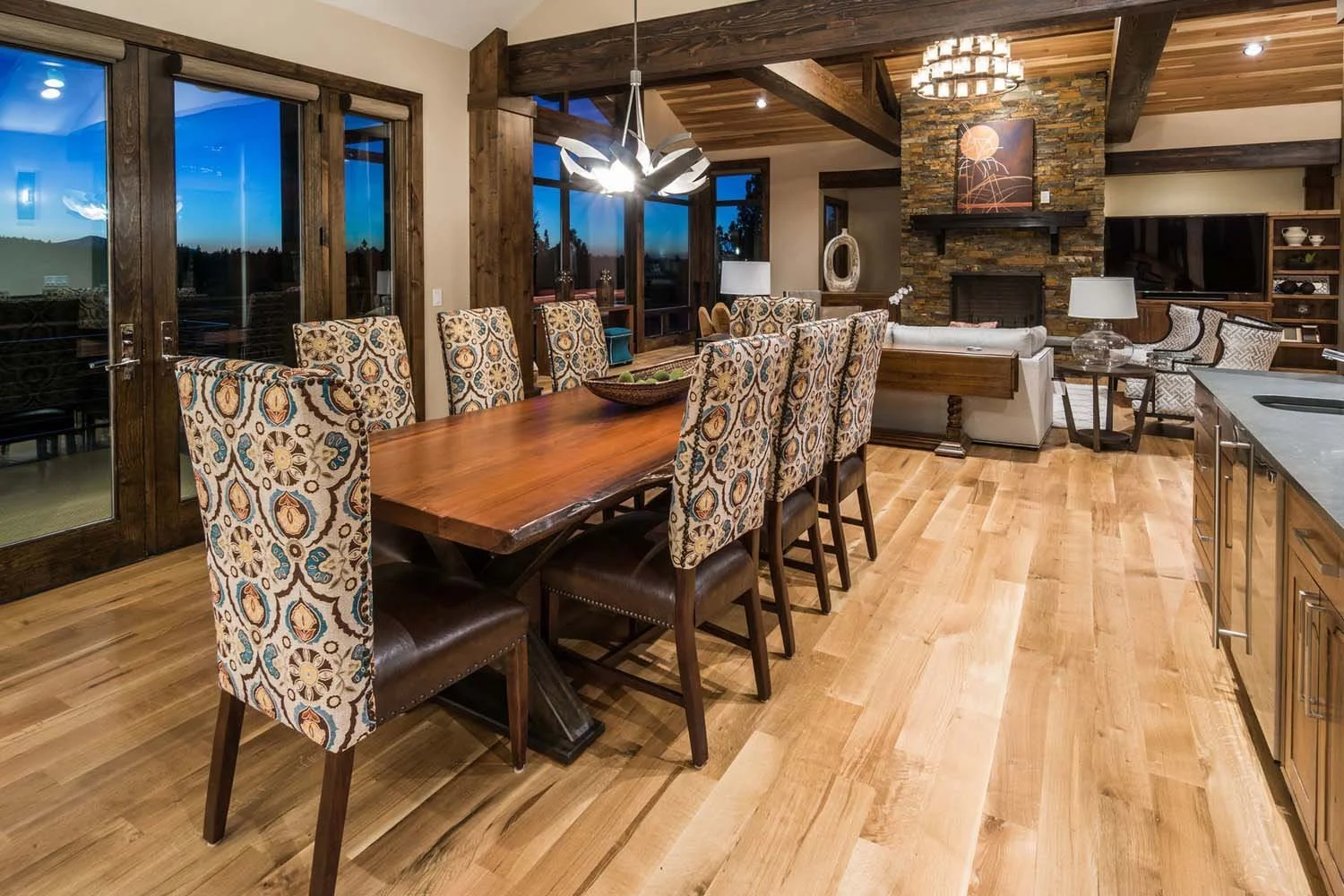 This spacious open-concept living and dining area at the award-winning North Rim - Wild Rye home, built by Pacwest Builders, is a perfect blend of elegance and comfort. The space features beautiful wooden flooring, a stunning stone fireplace, and mod