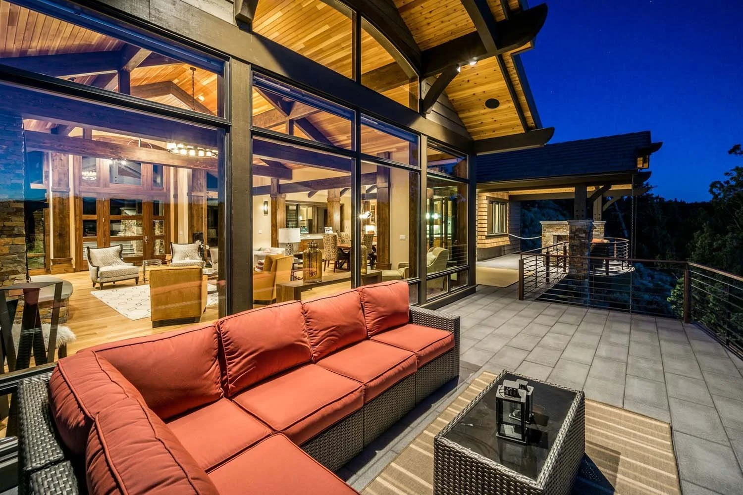 This peaceful outdoor balcony at the award-winning North Rim - Wild Rye home, built by Pacwest Builders, is a perfect spot to unwind after a long day. The spacious area features a comfortable sectional sofa and a wicker coffee table with a charming l