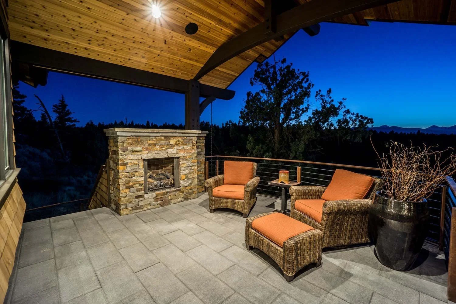As experienced builders of luxury custom homes in Central Oregon, Pacwest Builders crafted this ultimate outdoor oasis at North Rim - Wild Rye. This image highlights the spacious balcony, with its inviting stone fireplace and comfortable seating with