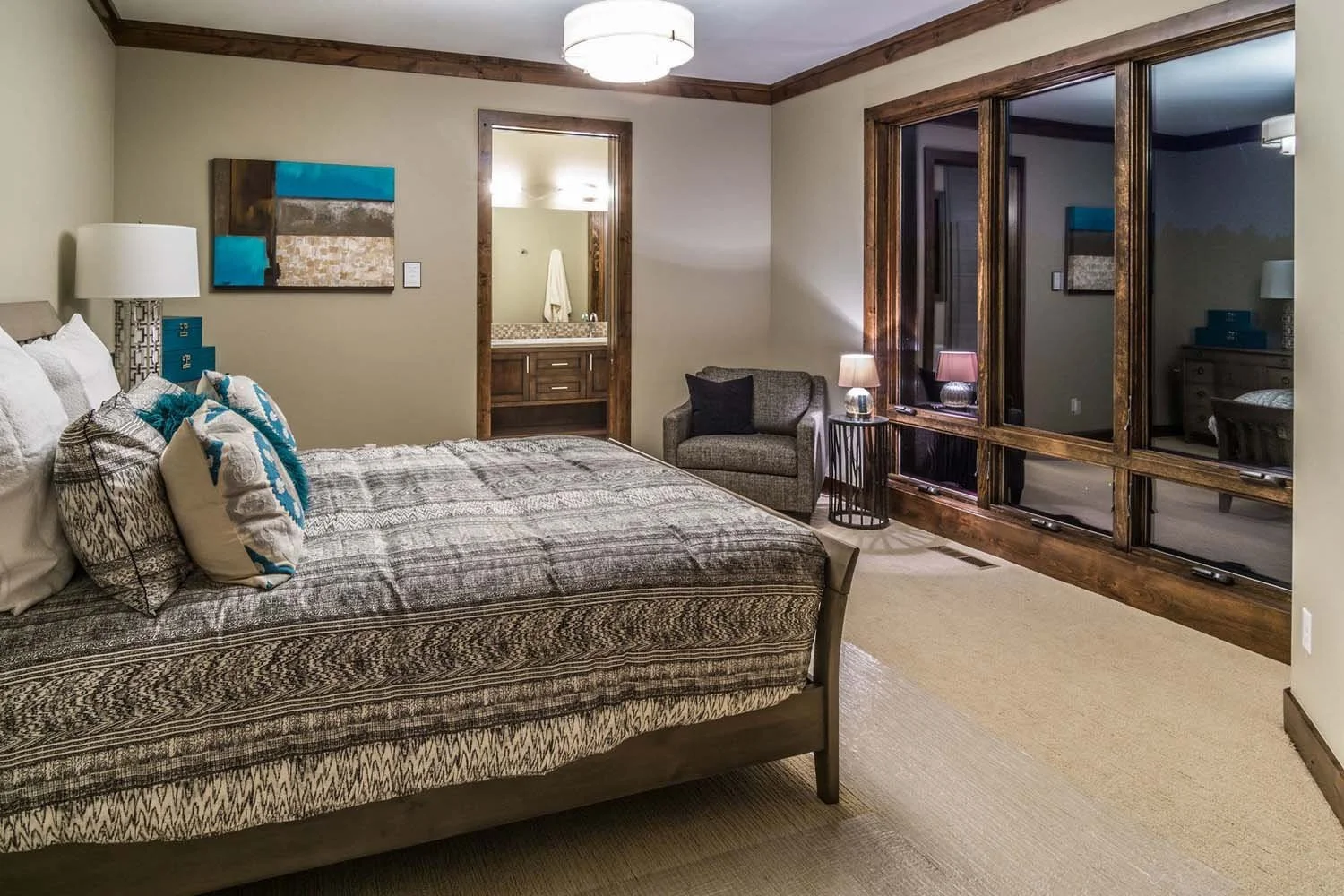 As experienced builders of luxury custom homes in Central Oregon, Pacwest Builders crafted this award-winning master suite at North Rim - Wild Rye. The space, with interiors by Kristy Yozamp, features a large bed and a small armchair, creating a sere