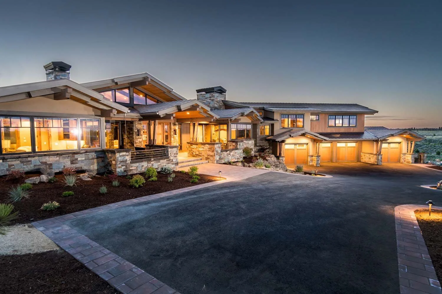 This spectacular modern house at Tetherow - Hawk Court in Central Oregon by Pacwest Builders is a beautiful blend of natural materials and sleek design. This image highlights the home’s striking architecture, with a beautiful stone, wood, and glass e