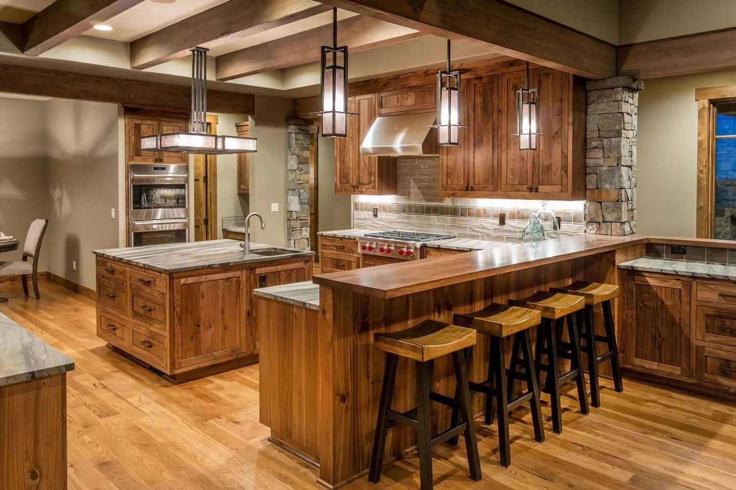 This spacious kitchen at Tetherow - Hawk Court in Central Oregon by Pacwest Builders is a perfect blend of style and functionality. The space, with interiors by Kristy Yozamp, is defined by its beautiful wooden cabinetry and a striking central island