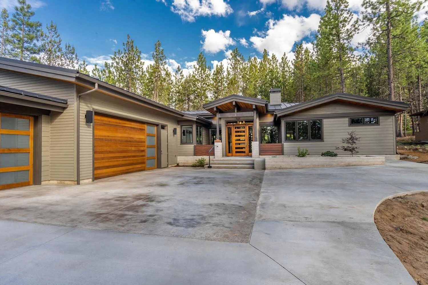 This spectacular front entrance in the "Best of Show" winning home at Tetherow - Meeks Trail by Pacwest Builders is a testament to sophisticated design and functionality. The custom horizontal wood-paneled door with glass rectangles echoes the wooden