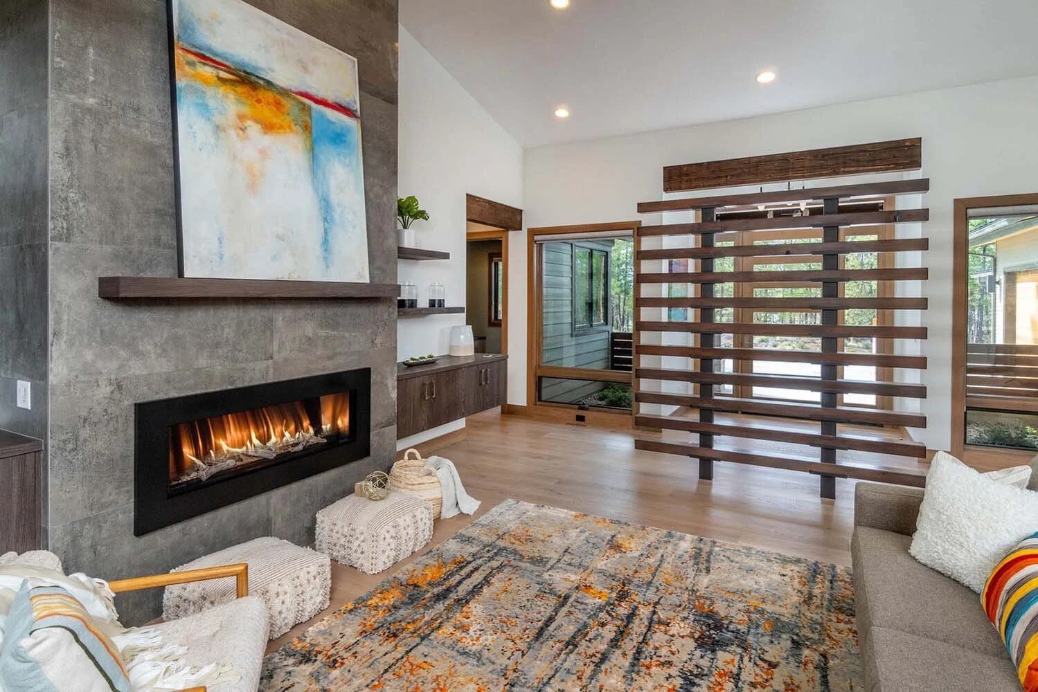 This creative living room at Tetherow - Meeks Trail by Pacwest Builders is a perfect blend of modern design and unique artistry. The wide modern stone fireplace is the centerpiece of the room with beautiful abstract wall art displayed. The space is a