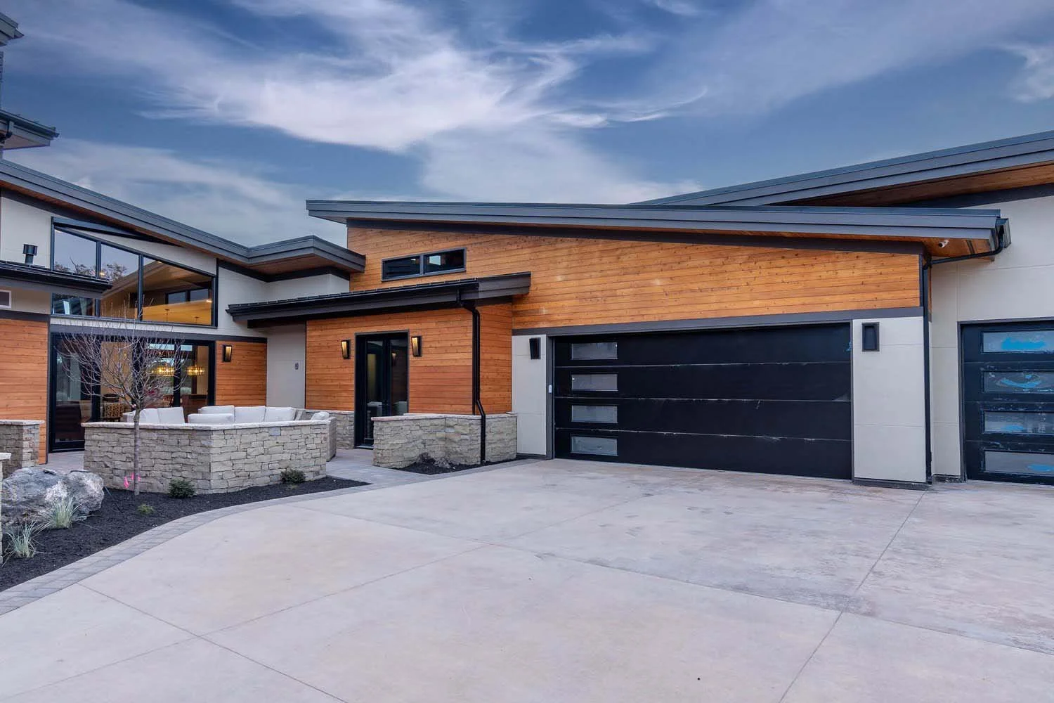 Designed by Blair Davis, this Pronghorn - Switchback home highlights its modern architecture through a mix of materials. Large black metal garage doors stand out against the wood and concrete exterior, and the thoughtfully designed outdoor seating ar