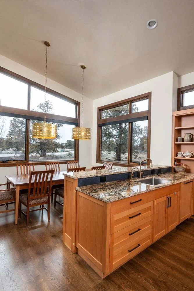 A perfect blend of functionality and style, the kitchen and dining area of this Pronghorn - Switchback residence highlights its expert architecture. Wooden cabinets, granite countertops, and a breakfast bar create a welcoming kitchen space that leads