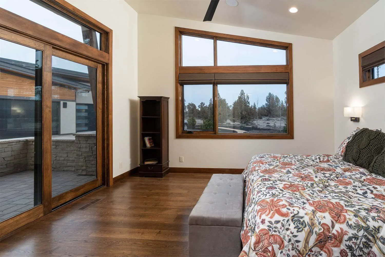 This serene bedroom is a highlight of a luxury custom home in Central Oregon, built by Pacwest Builders. The space is a perfect blend of architecture and interior design, featuring beautiful wooden floors and large windows that connect the room to th