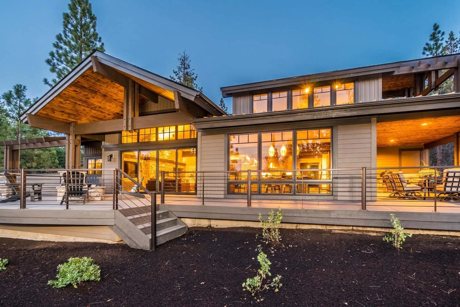 This mountain modern residence in Tetherow - Bainbridge Court, a 2017 COBA Tour winner, showcases stunning architecture by Spencer Williams. The house features a striking wooden exterior and large windows that are beautifully illuminated from the ins