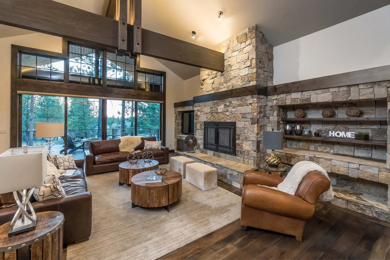 This stunning living room, a key feature of this Central Oregon home, is a testament to the masterful interior design by Kristy Yozamp. The room, with its large windows and a beautiful stone fireplace, creates a warm and inviting atmosphere. The desi