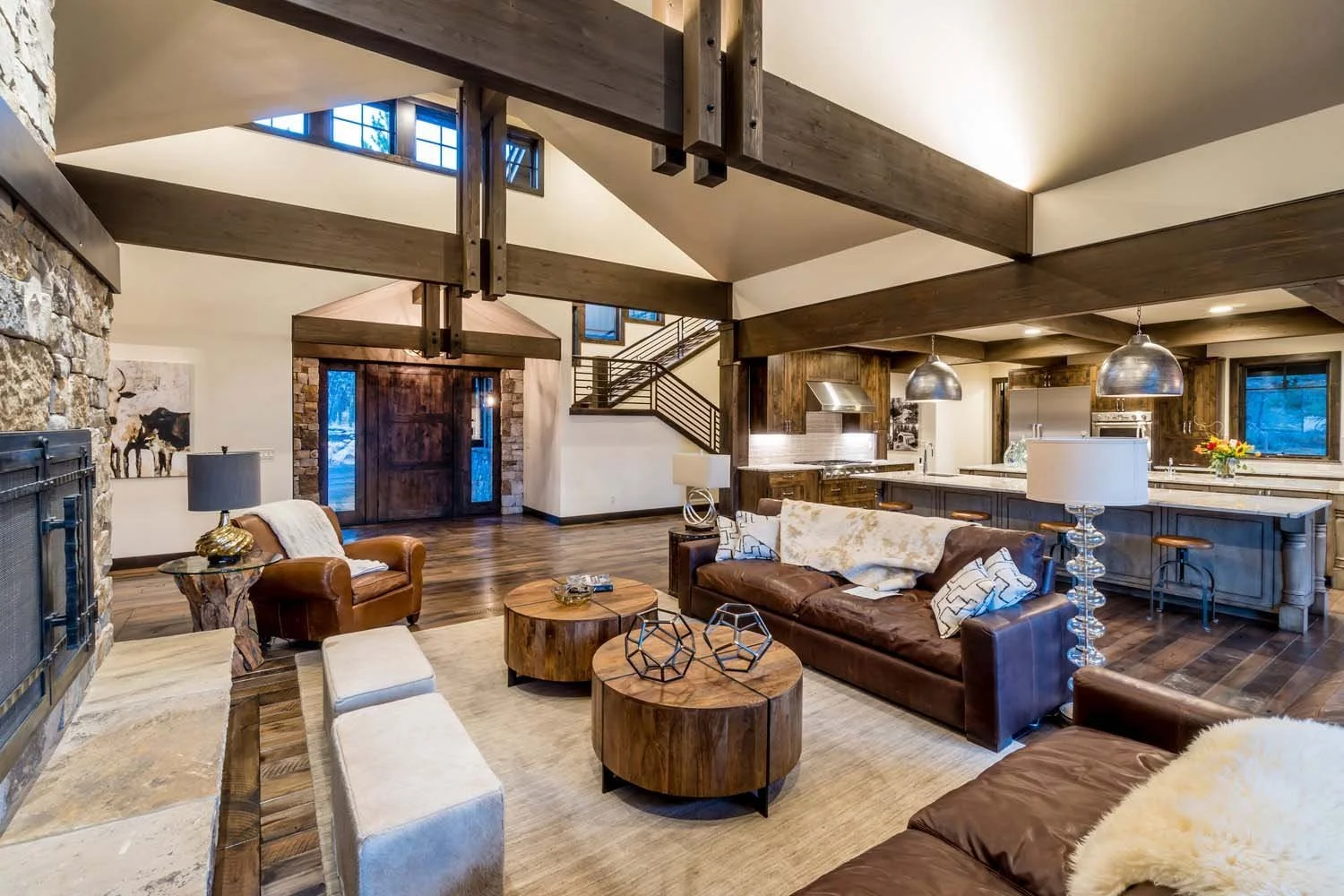 Explore the award-winning architecture of this open-concept space in Tetherow - Bainbridge Court. Designed by Spencer Williams, the living room and kitchen feature beautiful wooden beams, a stone fireplace, and a staircase. The interior design by Kri