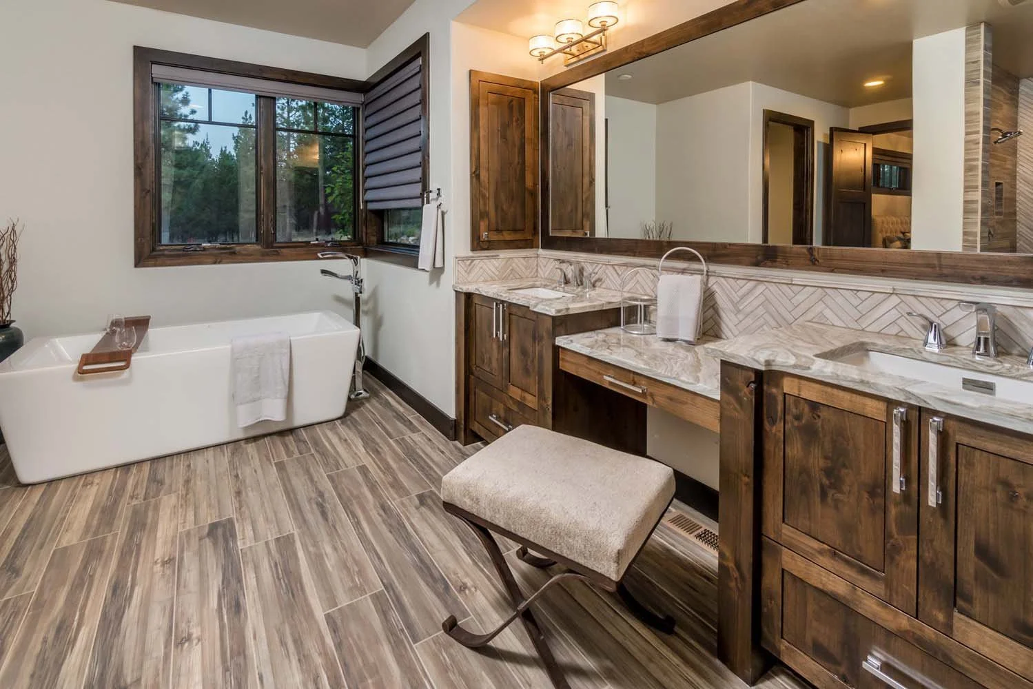 A modern bathroom with a freestanding tub and wood accents designed by Spencer Williams, part of the Tetherow - Bainbridge Court project in Central Oregon.