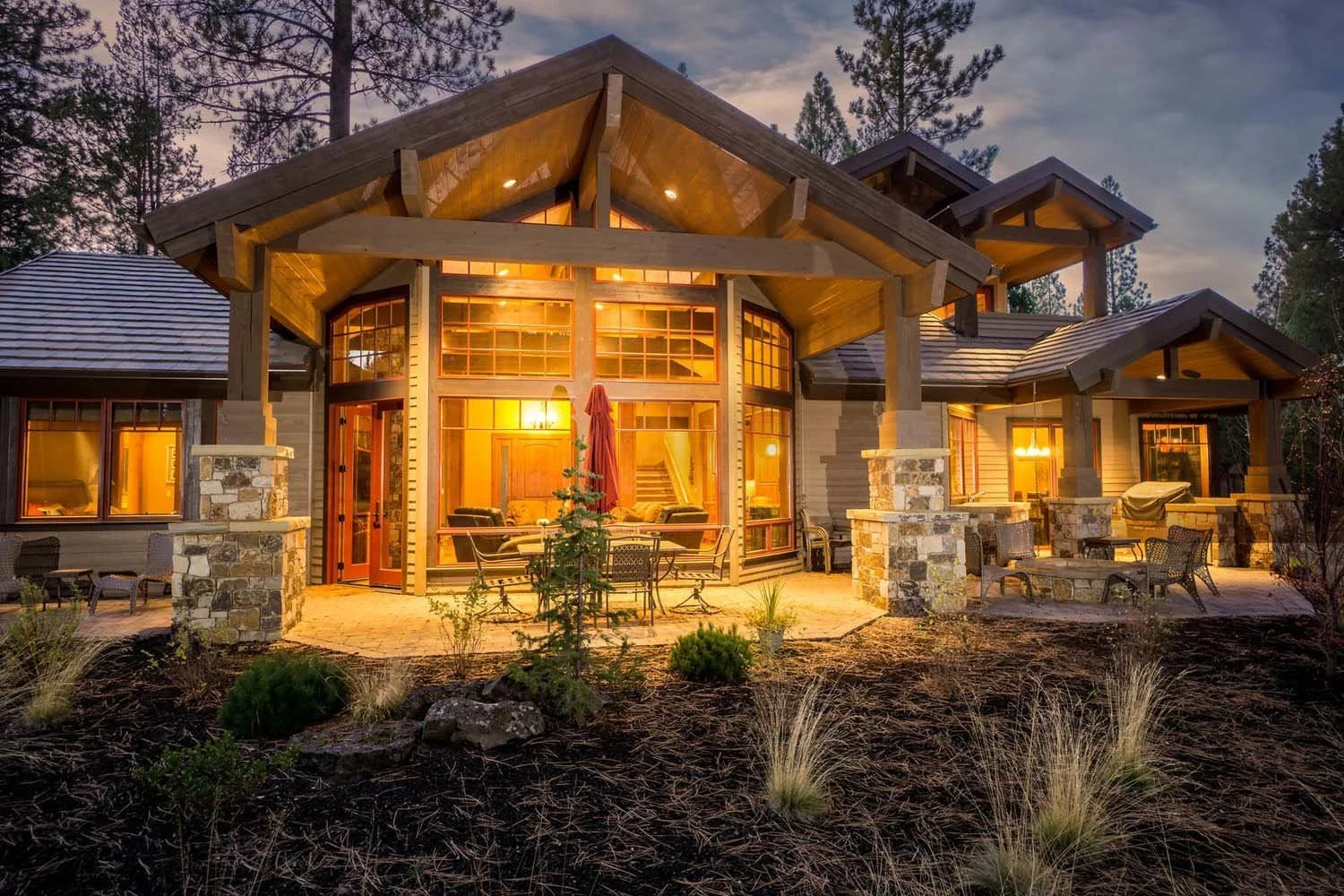 Designed by Spencer Williams, this mountain modern house in Central Oregon's Caldera Springs won "Best Architectural Design" and "Best of Show" for its category. The image shows the home's striking exterior with large glass windows, a beautifully lan