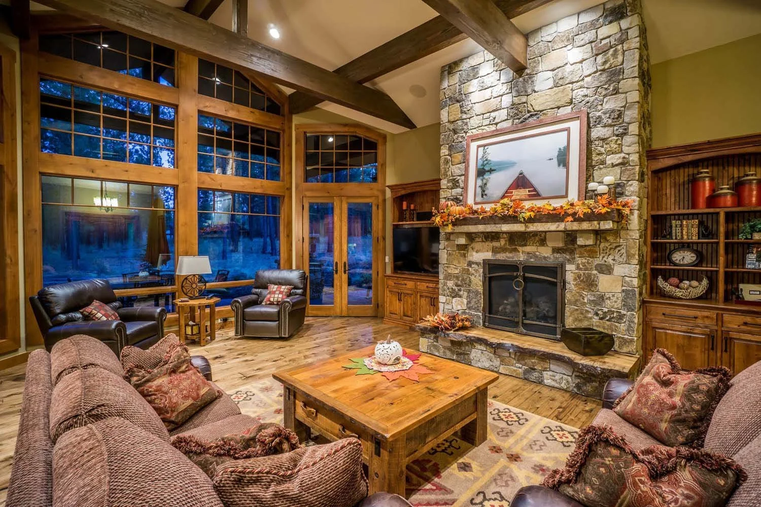 Cozy up with a view! This award-winning living room from the Caldera Springs - Fireglass Loop home, designed by Spencer Williams, is a perfect blend of comfort and nature. It features a beautiful stone fireplace, inviting leather chairs, and large wi