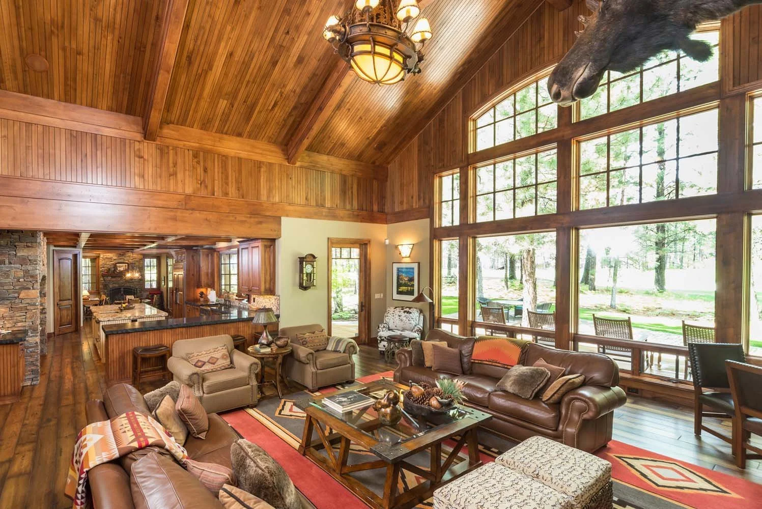 This living room, a highlight of a luxury custom home in Black Butte Ranch - Foin Follette, showcases masterful interior design by Kristy Yozamp. The space, designed with a high wooden vaulted ceiling and large windows, brings the outdoors in, a key