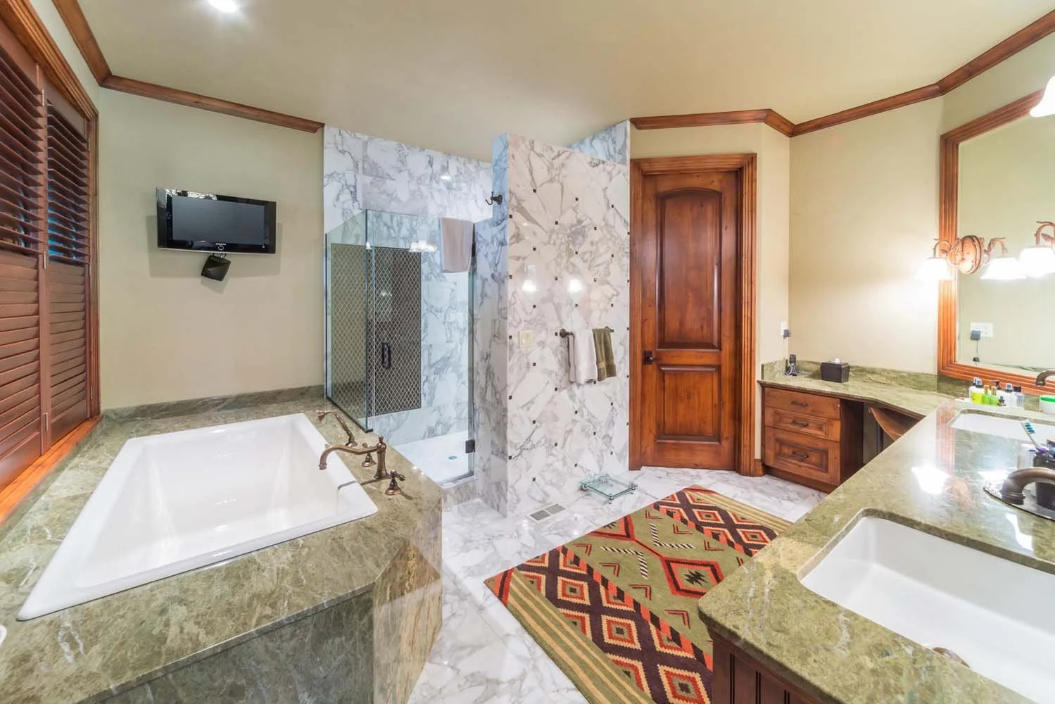 This luxurious bathroom in Black Butte Ranch - Foin Follette is a true Central Oregon retreat. The space, with two sinks, a bathtub, and a walk-in shower with beautiful marble walls, showcases impeccable interior design by Kristy Yozamp. The inclusio
