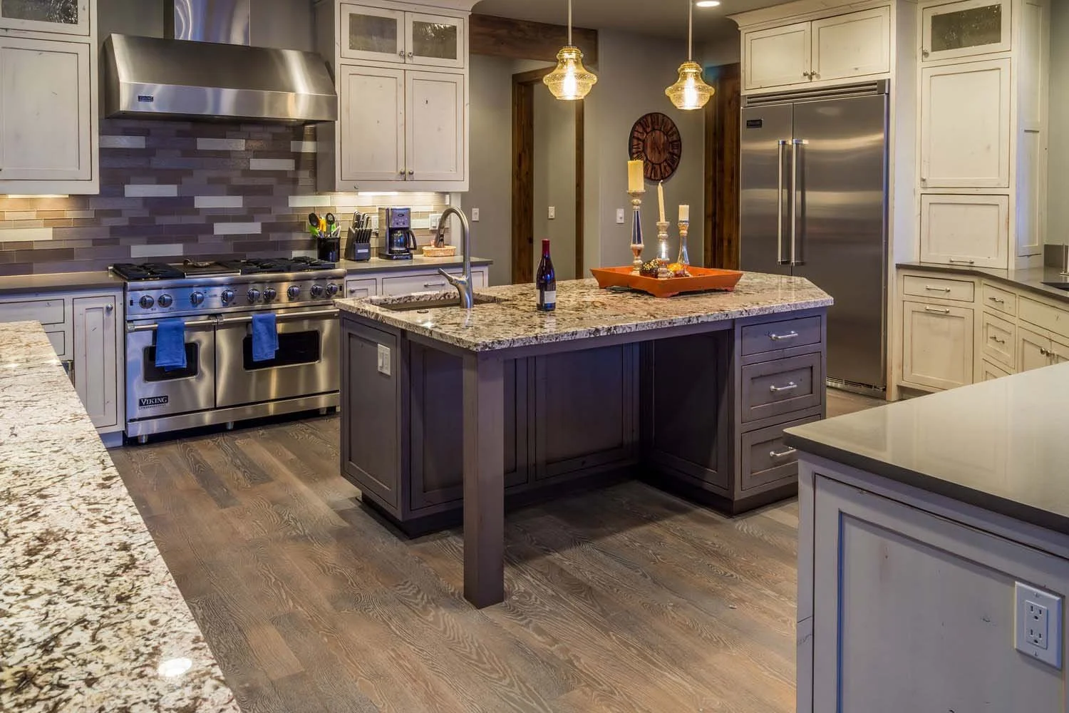 This masterful kitchen is a highlight of this Central Oregon residence, a showcase of purposeful architecture design by Spencer Williams. The space features a large island with a granite countertop, stainless steel appliances, and beautiful wooden ca
