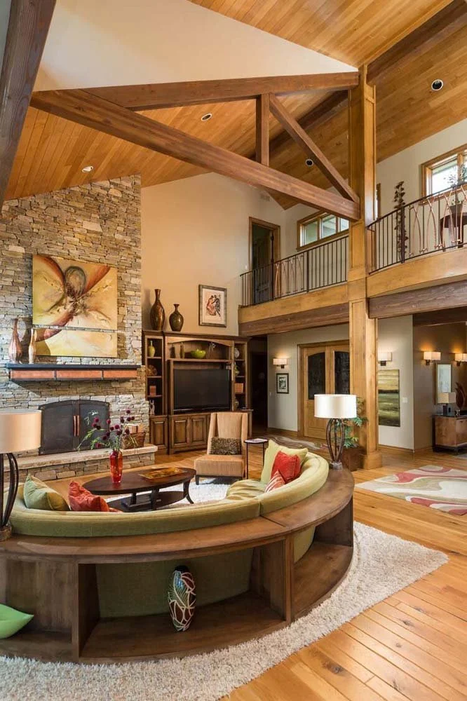 This spacious living room in Tetherow - Skene Trail, a luxury custom home, is a distinguishing characteristic of masterful interior design by Kristy Yozamp. The space, with its high wooden ceilings and large windows, is designed to bring in natural l