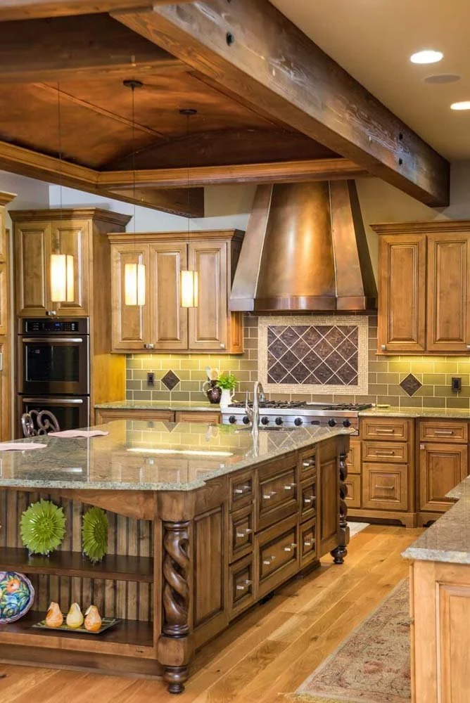 This rustic modern kitchen, a cornerstone of a luxury custom home in Tetherow - Skene Trail, is a beautiful showcase of interior design by Kristy Yozamp. The space features wooden cabinets, a central island with a granite countertop, and a stainless