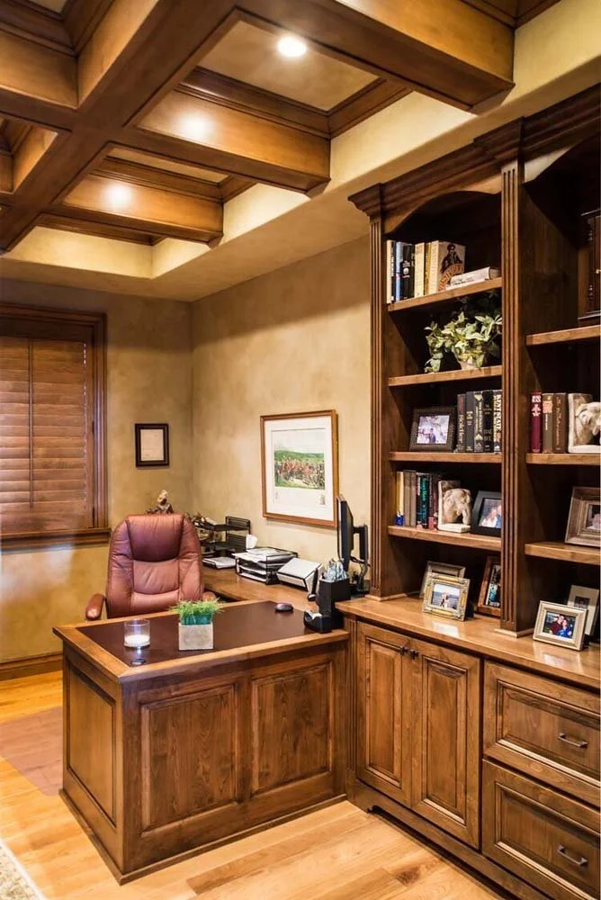 This home office, a key feature of a luxury custom home in Tetherow - Skene Trail 1, showcases masterful interior design by Kristy Yozamp. The space, with its elegant wooden desk and bookshelf, and a comfortable leather chair, is both functional and