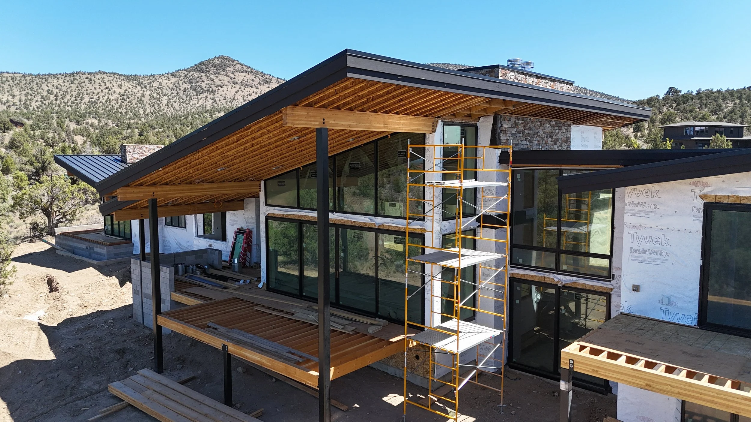 Mountain modern home in Brasada Ranch designed by Spencer Williams and built by Bend Oregon custom builder Pacwest Builders, featuring floor to ceiling glass, stone walls, and low slope tongue and groove roofs.
