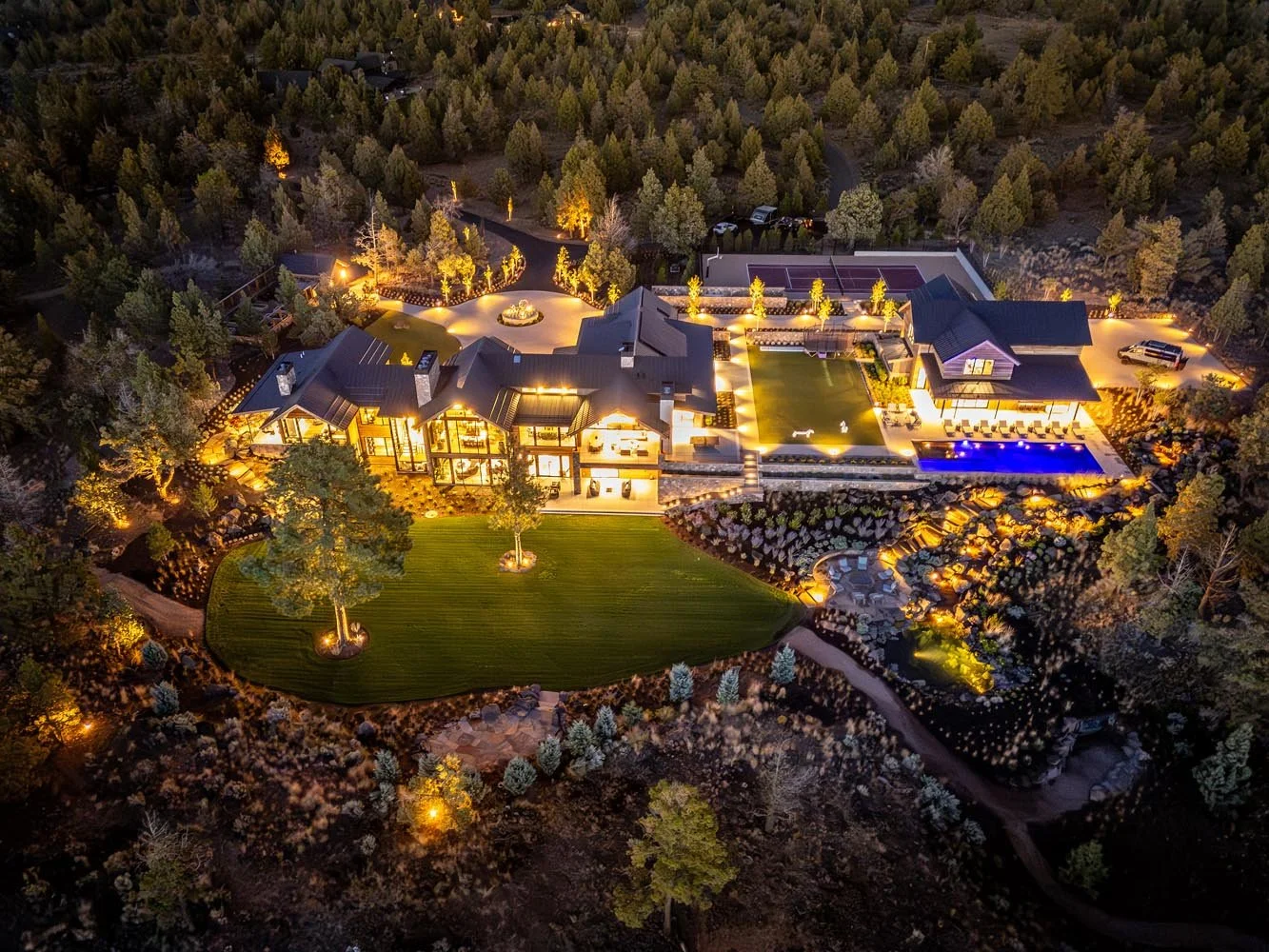 An impressive aerial nighttime view showcases the sheer scale of this luxury custom home in Pacific Cascade Heights, a custom build by Pacwest Builders with architectural design by Spencer Williams. This well-lit modern residence, with a stunning lan