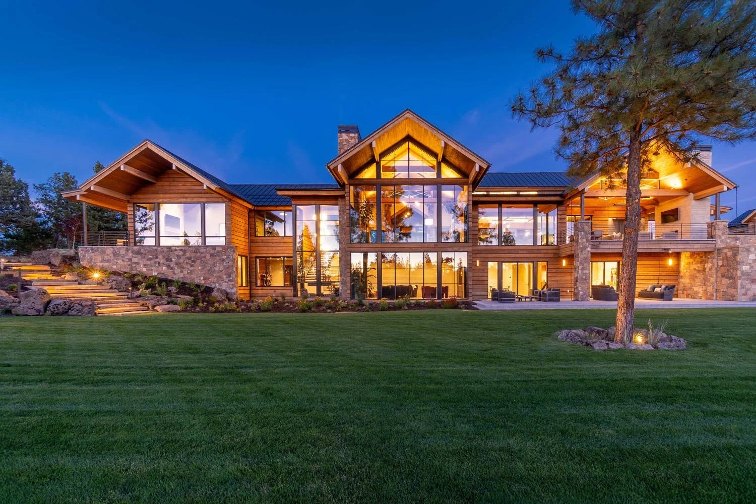 The grand front entrance of the mountain modern Pacific Cascade Heights home, designed by Spencer Williams, makes a striking statement. This luxury custom build by Pacwest Builders features expansive glass windows by Fleetwood Windows and Doors, whic