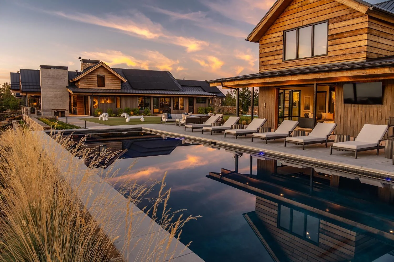 A beautiful sunset view at the Pacific Cascade Heights home, a custom build by Pacwest Builders, highlights its resort-style amenities and cohesive design. This luxury mountain modern backyard, with architectural design by Spencer Williams, comes to