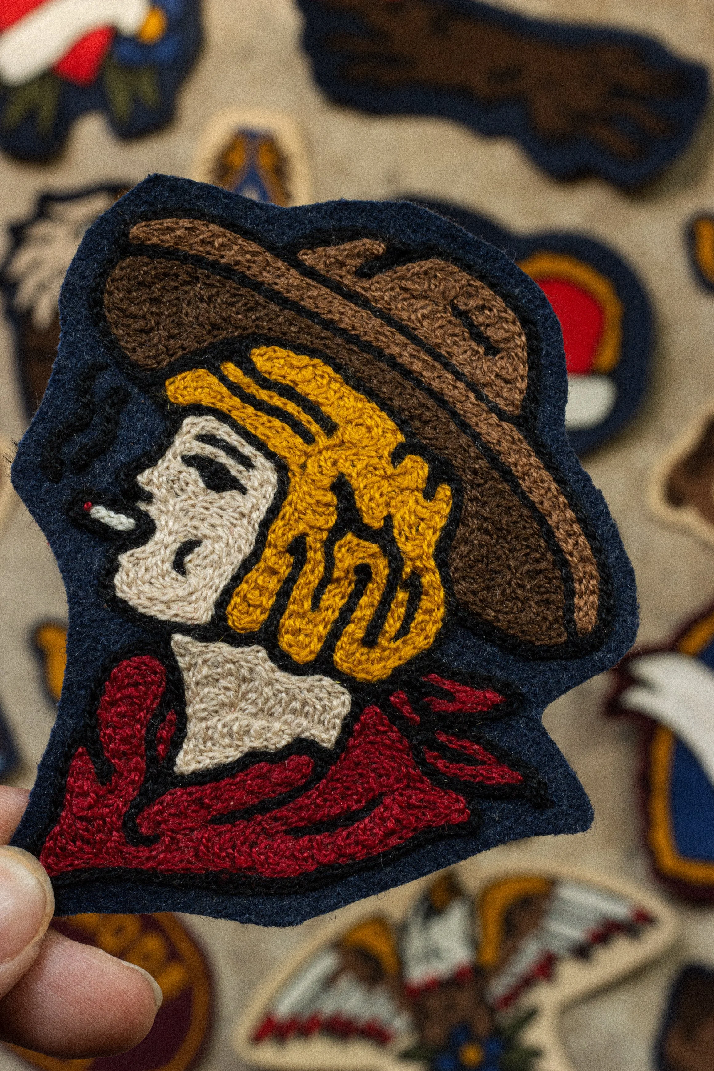 Custom chainstitch embroidery patch made in Dallas Texas using an antique Cornely machine. Chainstitched scrim felt patch of a cowgirl smoking cigarette. 