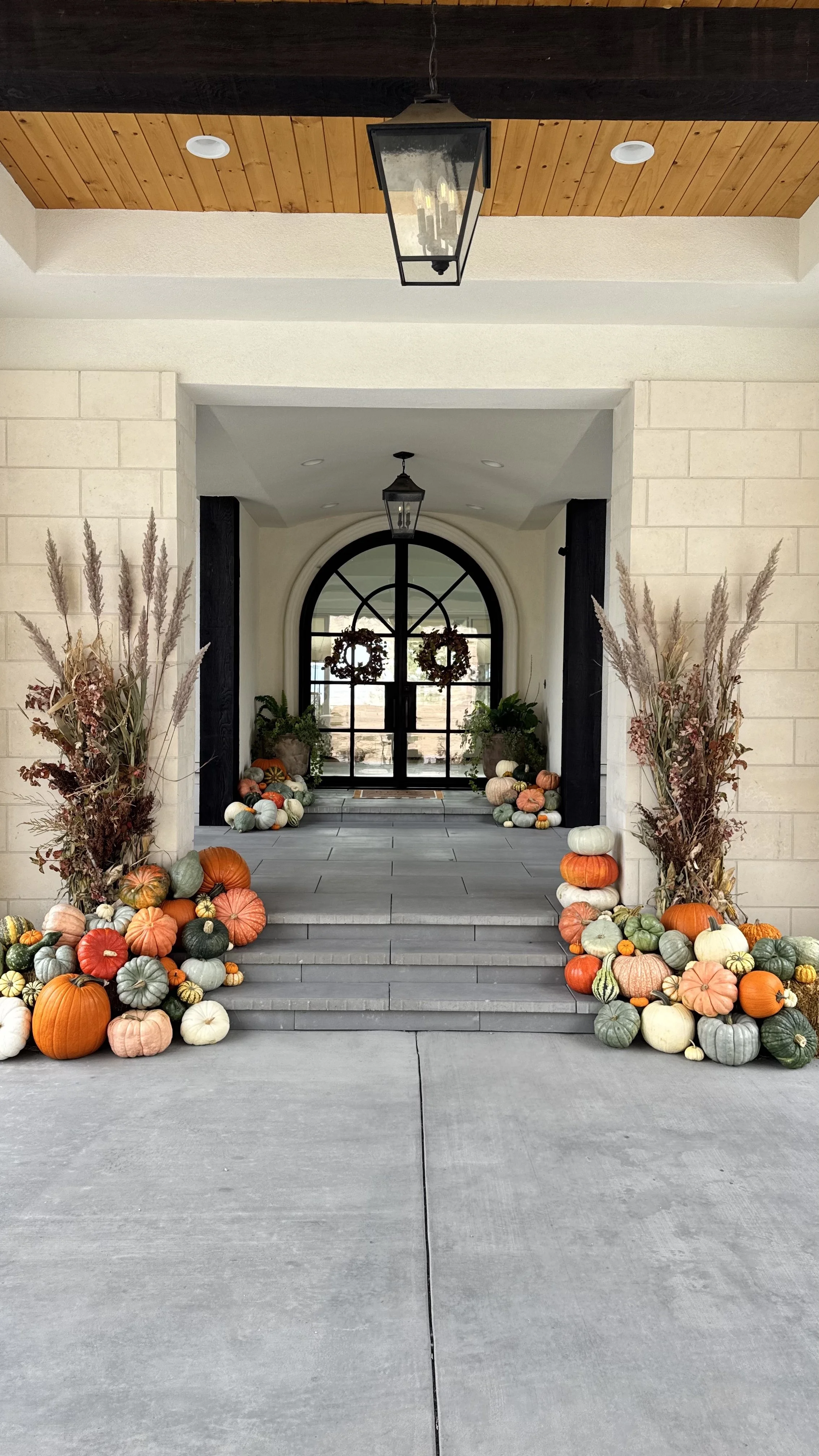 Decorative fall pumpkins and dried plants line the steps and entryway of a house.